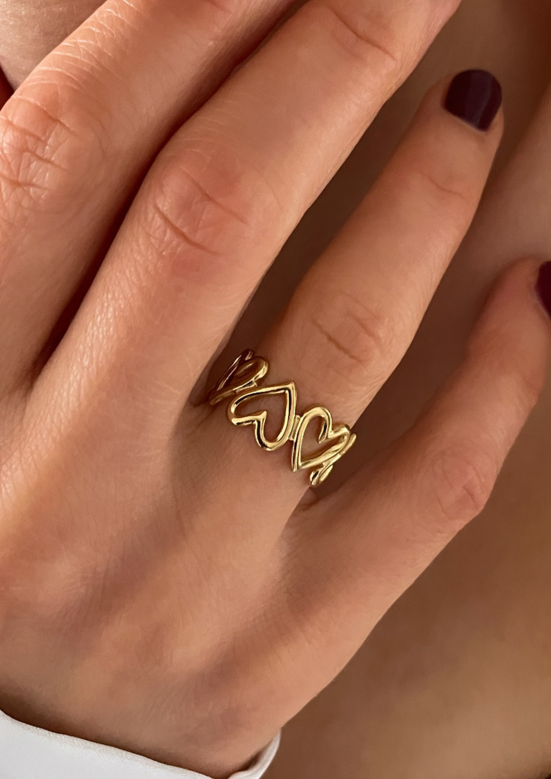 goldener Ring mit Herzdetails an Ringfinger getragen